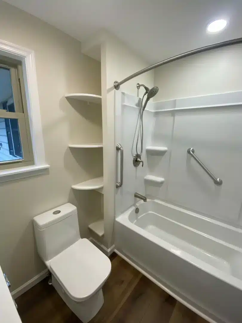 Remodeled bathroom with a new tub and shower surround, built-in shelving and a grab bar