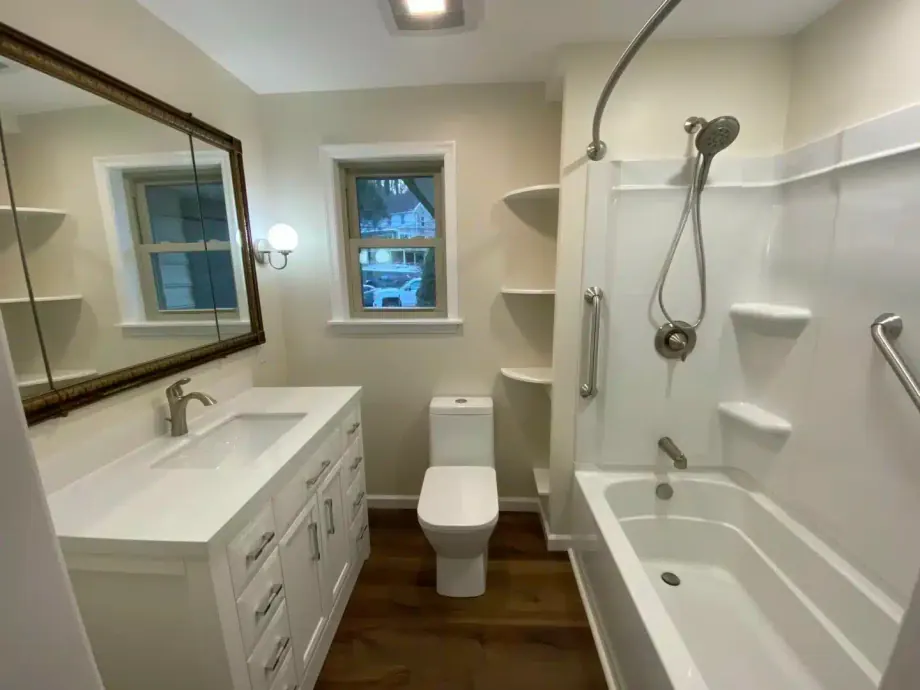 Finished bathroom remodel with a new vanity, large mirror, toilet and tub-shower combination