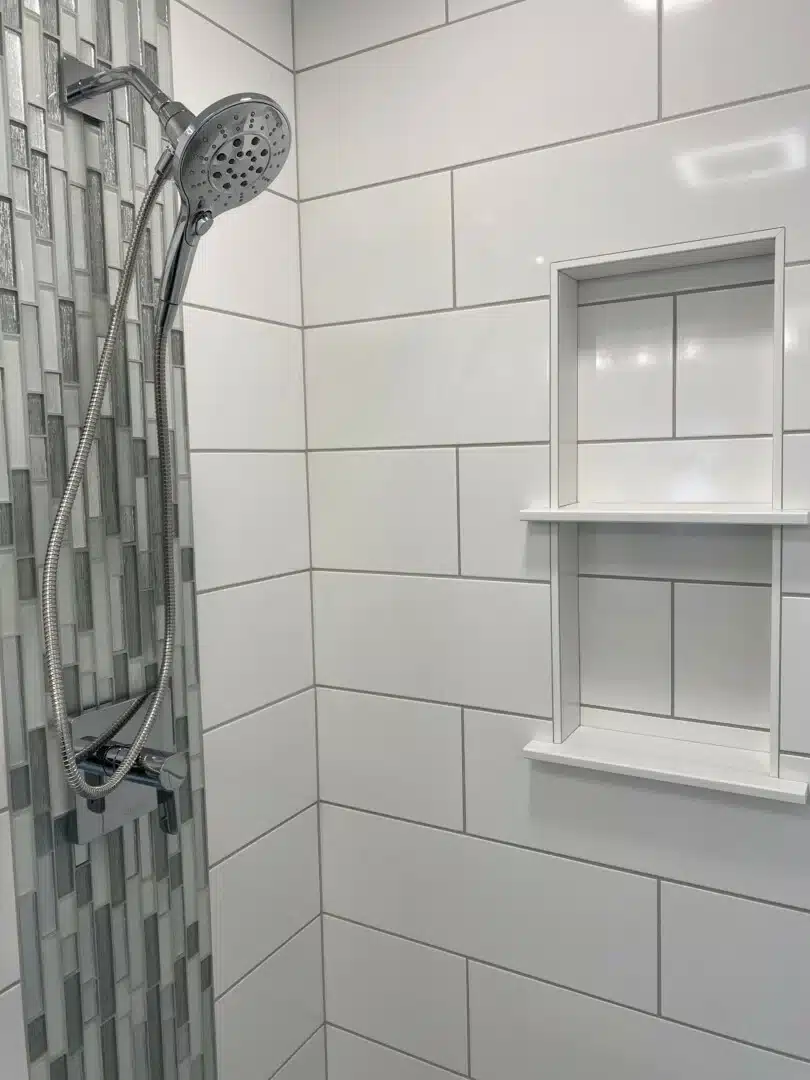 Custom tile shower with white tile, a built-in niche and a mosaic accent strip