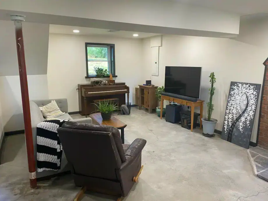 Finished basement family room with a TV wall, seating area and piano